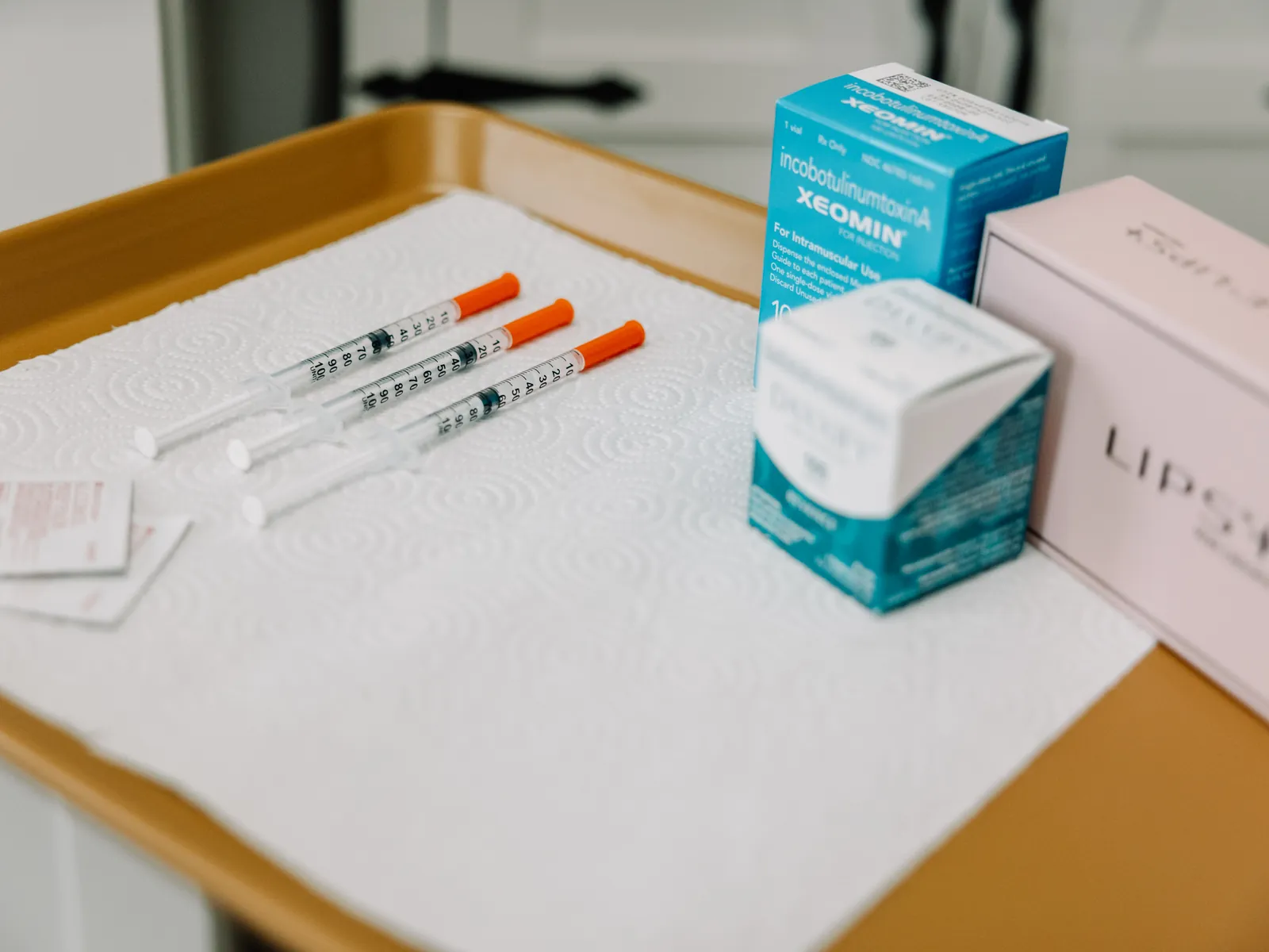 Filler syringes and product boxes laid out on a gold tray